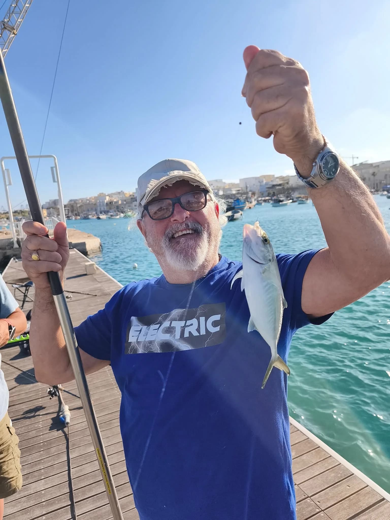A smiling angler showing a catch during a waterfront session