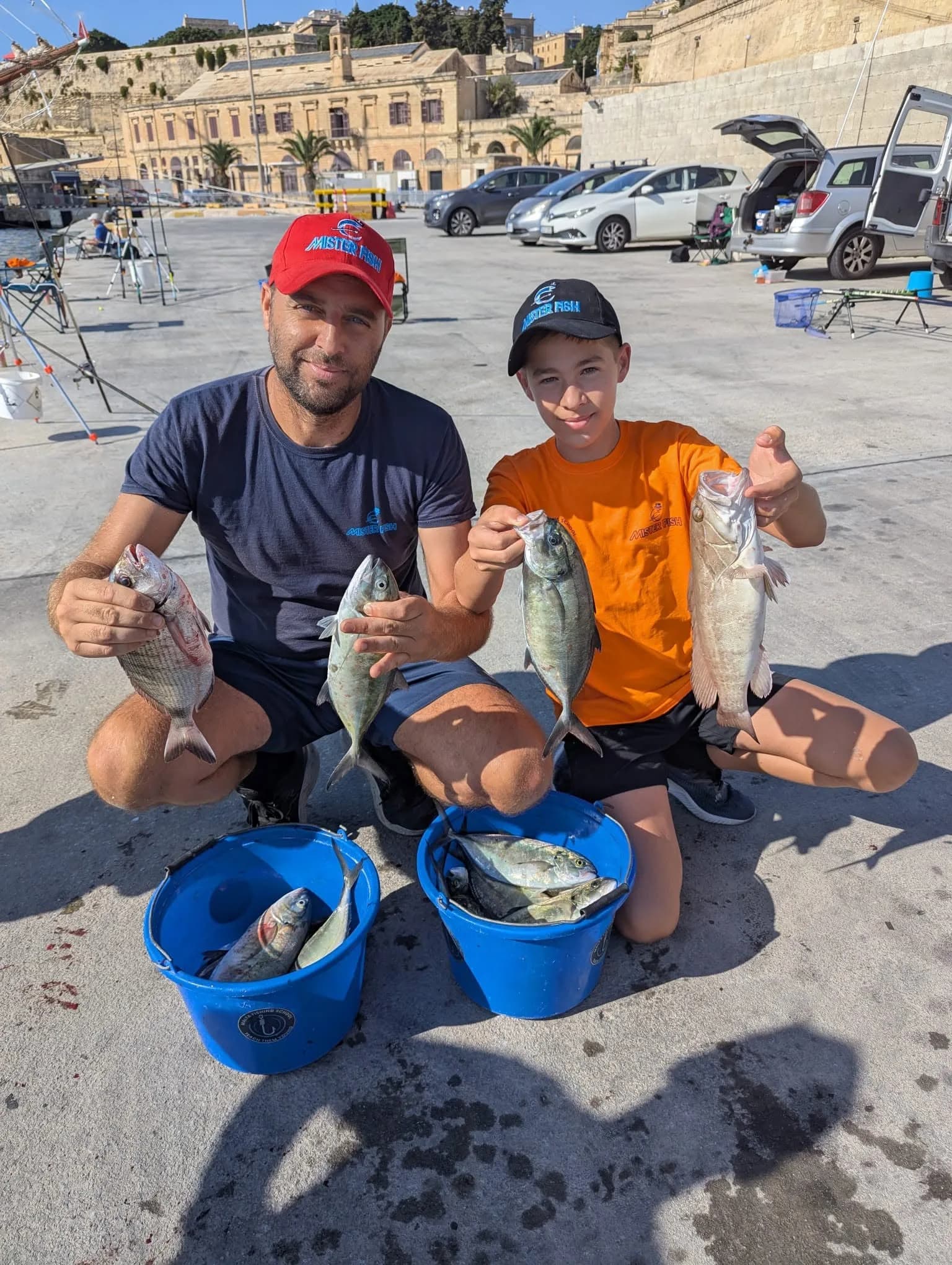 An adult and a young angler sharing their catches beside their fishing tackle