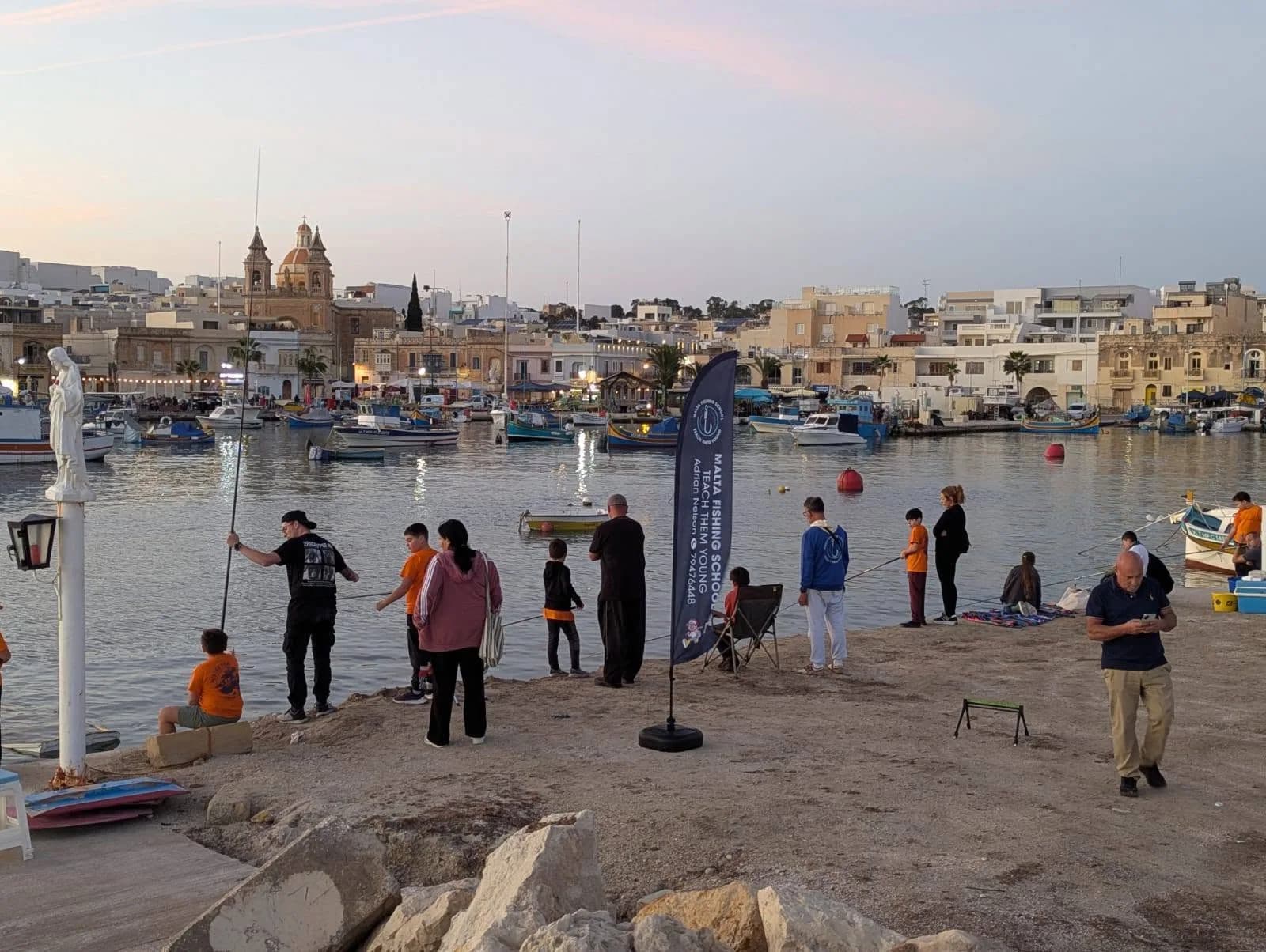A group fishing together along the waterfront in the evening